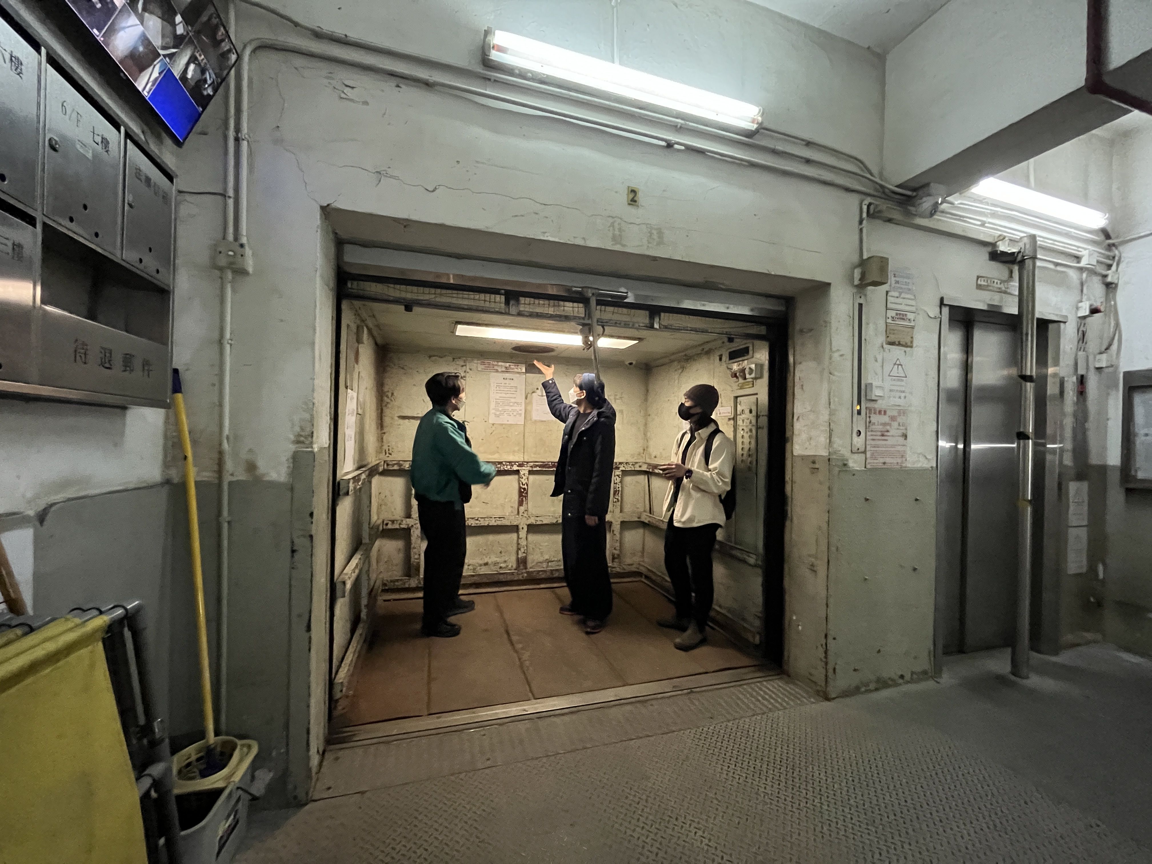 三人在一部残旧的载货升降机内观察其灯光。