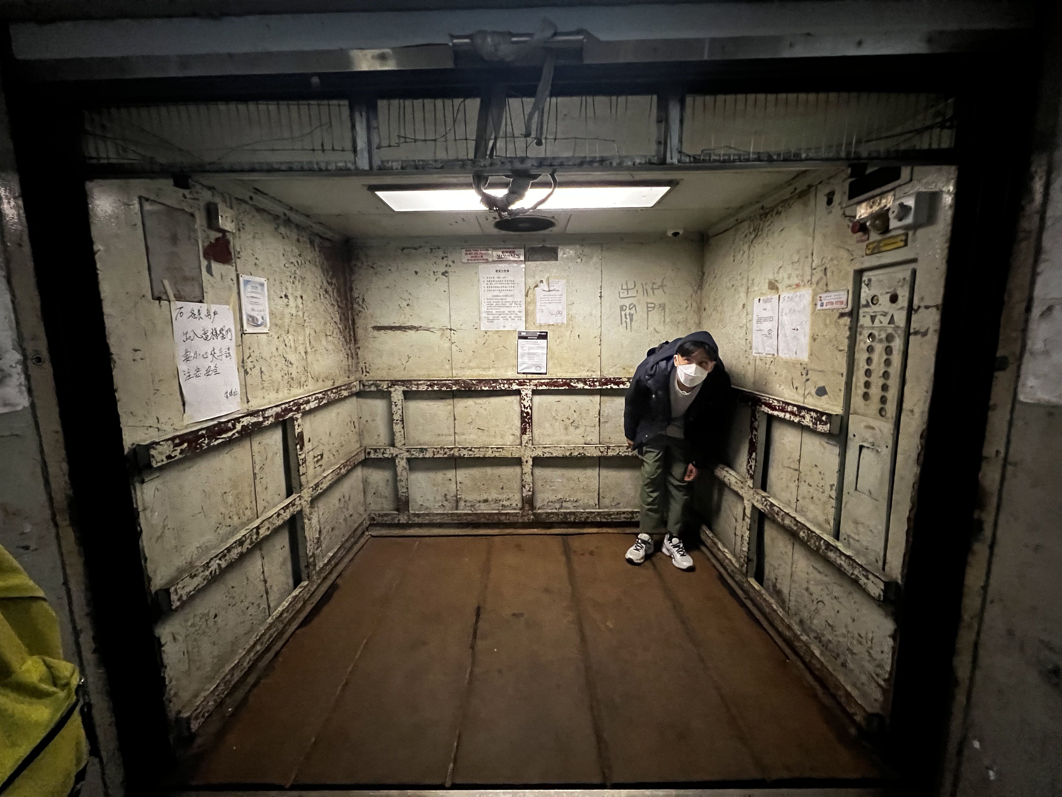 一个男人在一部残旧的载货升降机内弯着腰。