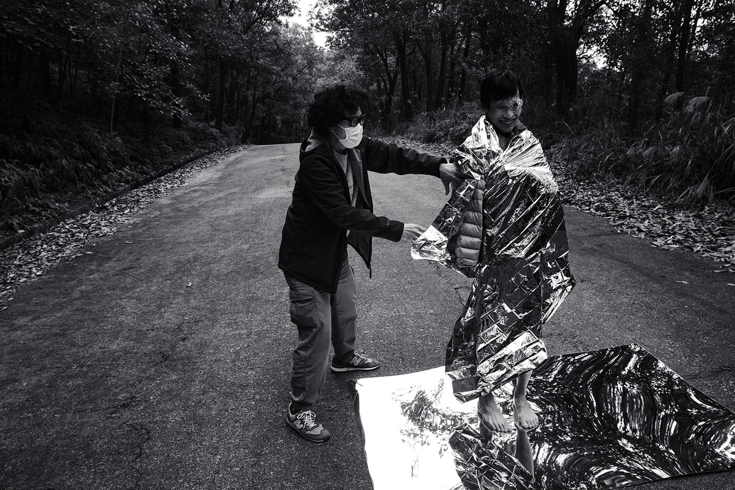 黑白照片中可见一名表演位和拍摄团队成员正为拍摄人做准备。表演者身上披着Mylar聚酯薄膜。