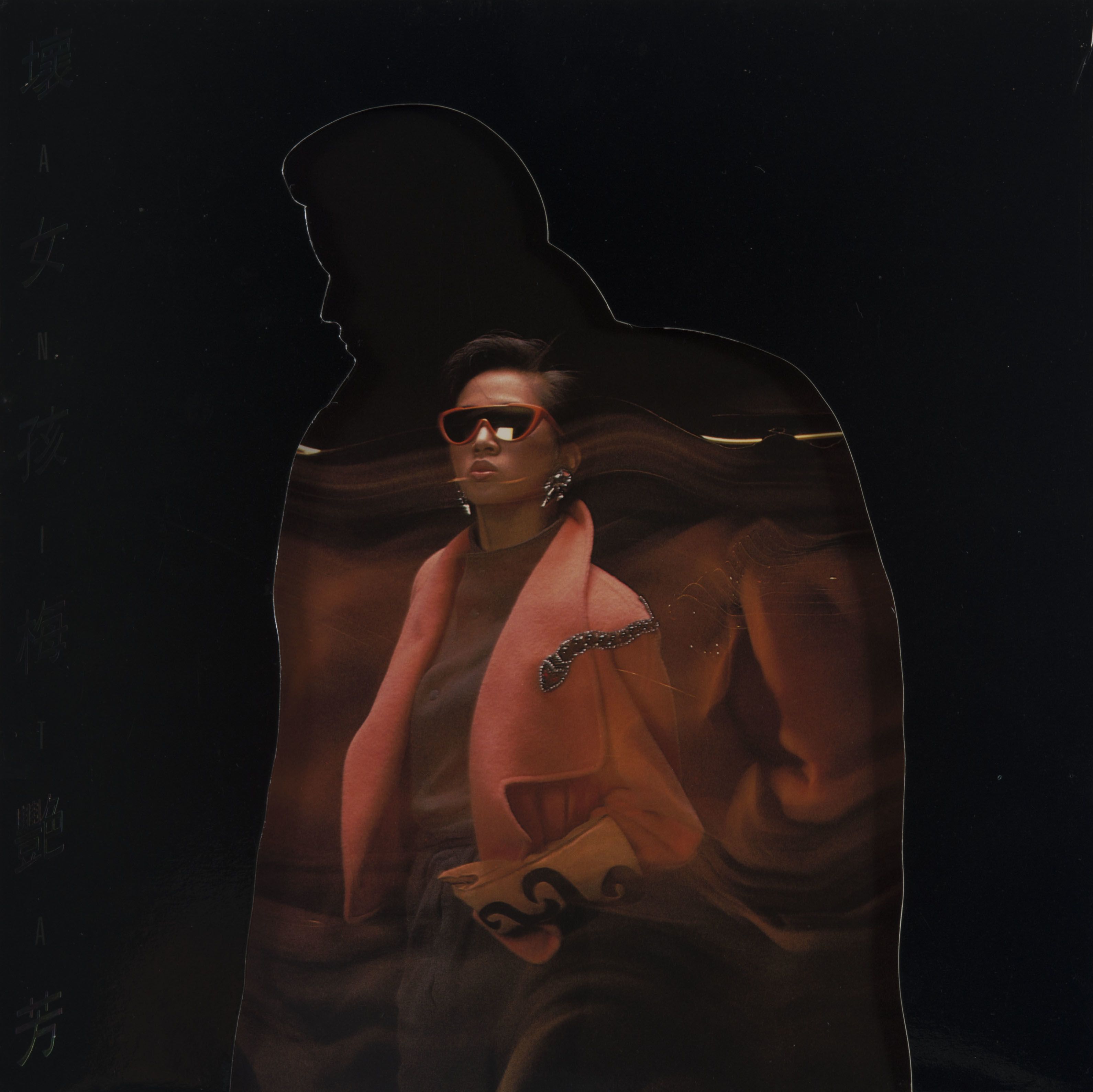 Jacket and inner page of Anita Mui’s vinyl album Bad Girl. The singer stands at the centre and has blurry reflections around her. Framed by a cut-out silhouette of a figure in an overcoat, she wears a coral jacket and a pair of sunglasses.