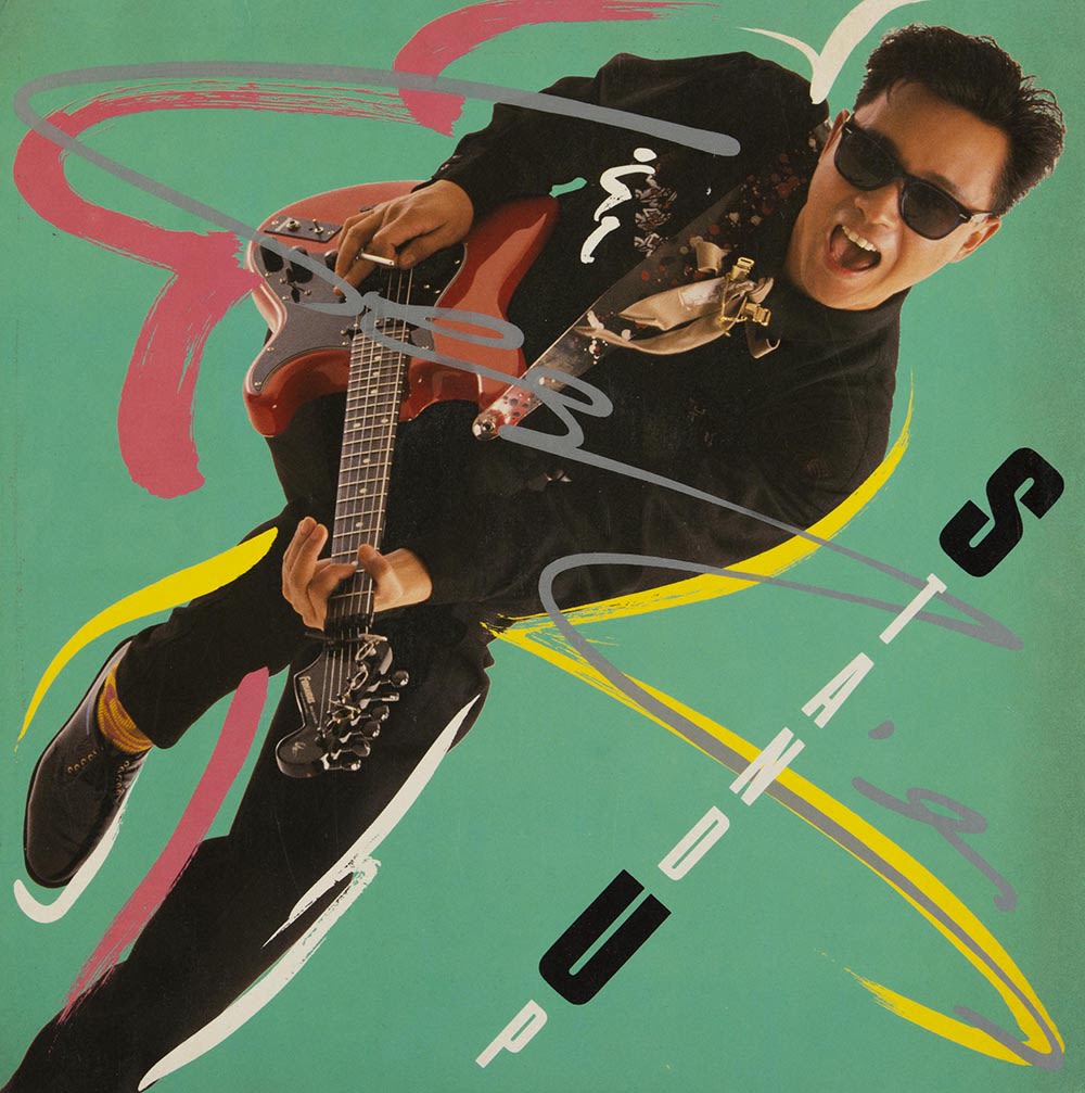 张国荣《Stand Up》黑胶唱片封面，右下方可见黑白色的直书标题。张国荣的半身照和标题往右转45度角。他身穿黑衣、戴太阳眼镜，弹奏着红色电子吉他。粉红、黄和白色的漩涡笔触在湖水绿色背景上包围着他。