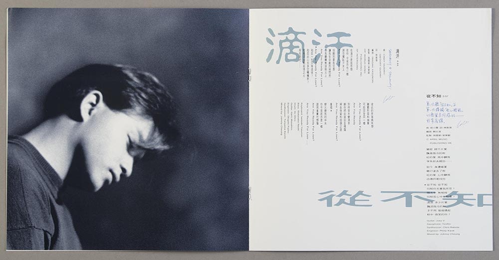 张国荣《Salute》镭射唱片歌词小册跨页。左页有张国荣的黑白侧面照，低头垂目。右页可见两首歌的歌词，浅蓝色的歌名和黑色的歌词以直书及横书方式排列。