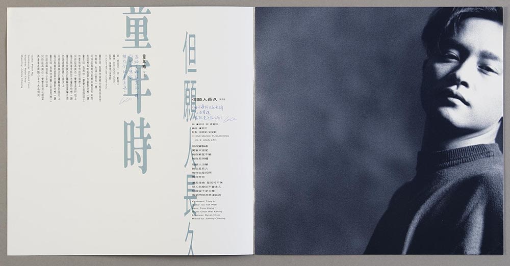 张国荣《Salute》镭射唱片歌词小册跨页。左方有两首歌的歌词，浅蓝色的歌名和黑色的歌词以直书及横书方式排列。右页则是张国荣的正面黑白肖像。