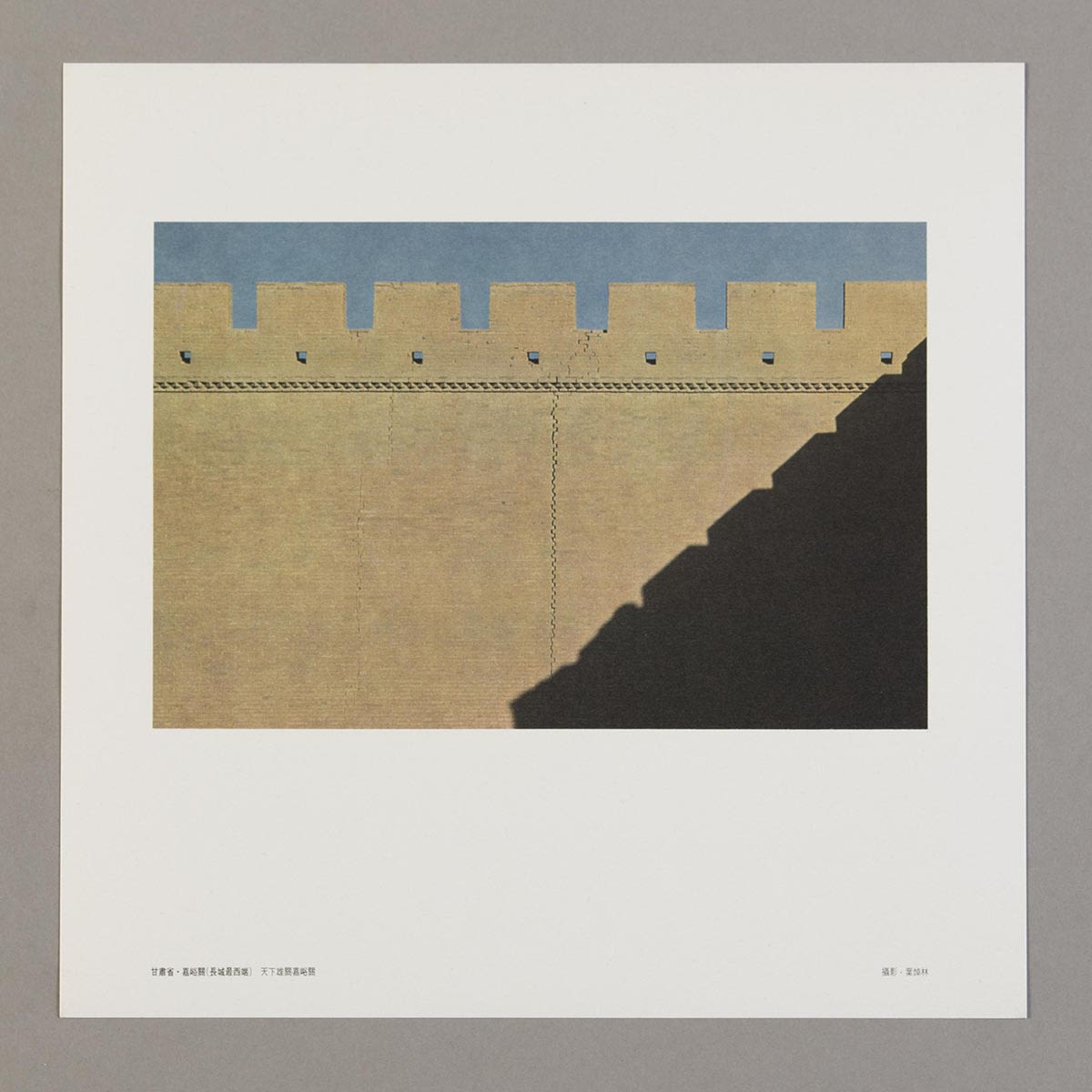 随《丝绸之路巡礼名曲集》黑胶唱片所附送的正方形明信片。白色边框内的照片可见嘉峪关带有女墙的城墙，右下方有分明的阴影。