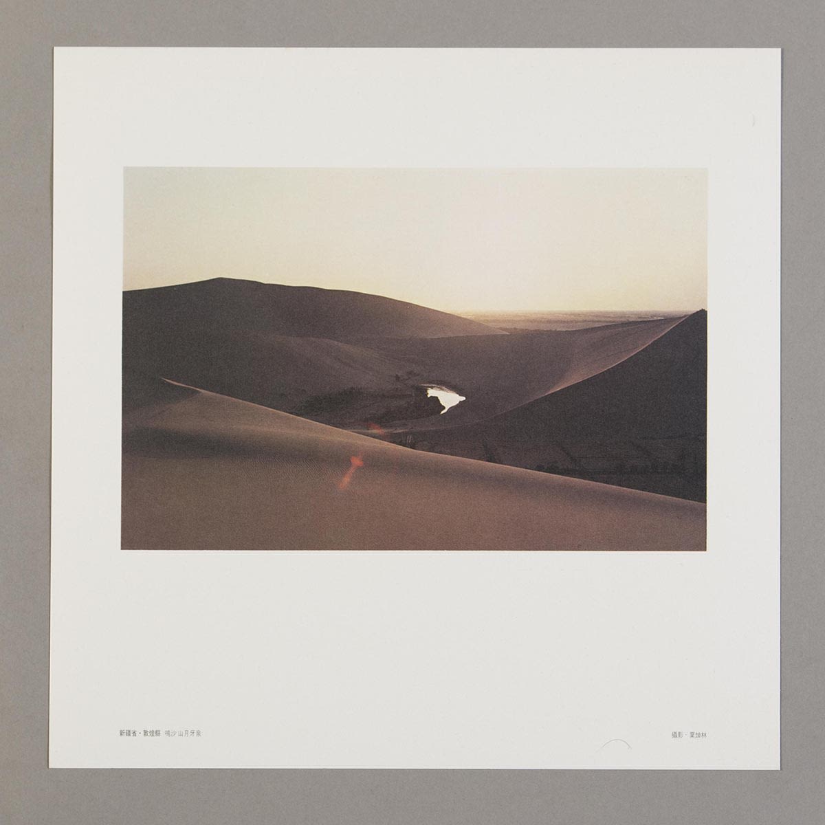 随《丝绸之路巡礼名曲集》黑胶唱片所附送的正方形明信片。白色边框内的照片有鸣沙山及中央的月牙泉。